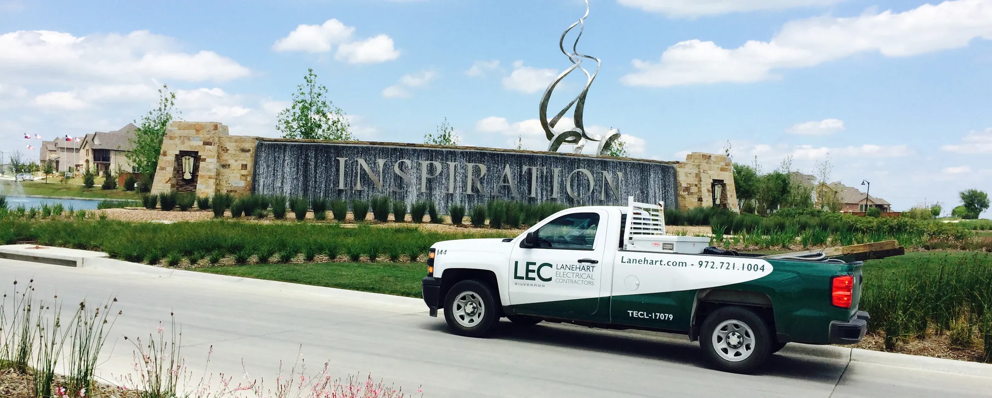 Lanehart Electrical Contractors truck at a new home community entrance under a wide Texas sky
